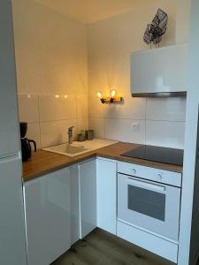 a white kitchen with a sink and a stove at Hossegor Vue Océan in Soorts-Hossegor +7 photos