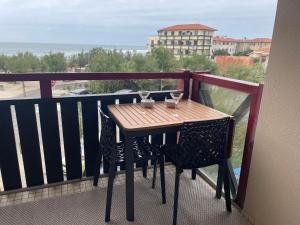 a wooden table with two glasses on a balcony at Hossegor Vue Océan in Soorts-Hossegor