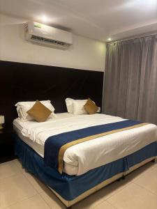 a bedroom with a large bed with a black headboard at Ramis Furnished Units in Buraydah