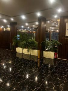 a lobby with two potted plants on a tiled floor at Ramis Furnished Units in Buraydah