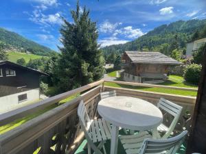 a table and chairs on a balcony with a view at Gemeaux B, appartement proche pistes de ski et village in La Clusaz +8 photos