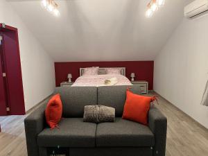 蒙斯Lauralys的一间卧室配有一张床和一张带橙色枕头的沙发。