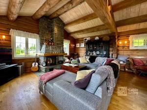 a living room with a couch and a fireplace at Large log cabin at Sjusjøen with sauna, fireplace and panoramic view in Ringsaker