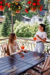 two women sitting at a picnic table on a balcony at Milli&Jon SPA in Bukovel