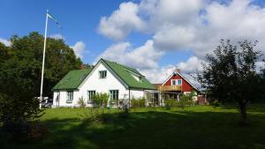 une maison blanche avec un toit vert et une maison rouge dans l'établissement Lilla Trulla Gårdshotell - Feels like home, à Bolestad