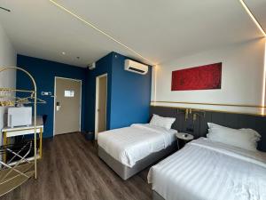 a bedroom with two beds and a blue wall at Regatta at Kozi Square Kuching in Kuching