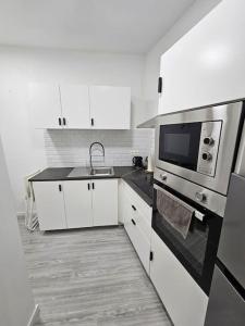 a white kitchen with a sink and a microwave at Sweet and chill studio center of Bruxelles # 2 in Brussels +6 photos
