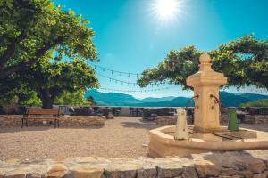 a fountain in a park with a view of the mountains at Logis Hôtel Restaurant Le Plantevin in Propiac