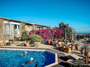 a couple of people swimming in a swimming pool at Cyprus Villages Hotel & Restaurant - Central Location - Bed & Breakfast - With Access To Pool And Stunning Views in Tochni