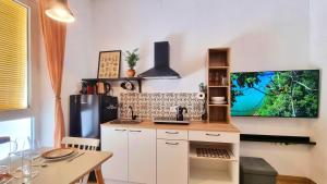 a kitchen with white cabinets and a tv on the wall at Rincón céntrico con encanto By Aloha Palma in Águilas