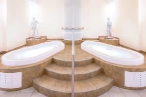 un bagno con due grandi vasche e due statue di Hotel Alex a Leukerbad