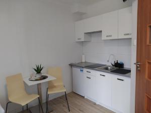 a kitchen with white cabinets and a table and chairs at Willa Epiona in Stepnica
