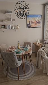 ein Esszimmer mit einem Tisch und einem Kronleuchter in der Unterkunft Cozy Apartman in Stara Pazova