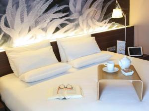 a bedroom with a bed with a book and a table at Novotel Barcelona City in Barcelona