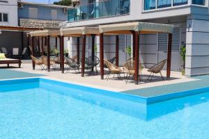 a pool with chairs and umbrellas next to a building at Holiday Park Verse in Ulcinj