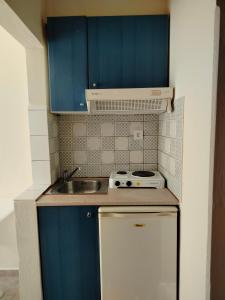a small kitchen with blue cabinets and a sink at Eirini's Hause in Nea Moudania