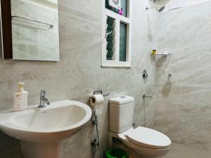 a bathroom with a sink and a toilet and a mirror at Olive Serviced Apartments HSR Layout in Bengaluru +40 photos