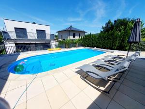 a swimming pool with two lounge chairs and an umbrella at Luxury Villa Vienna in Mauerbach