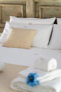 - un lit blanc avec des oreillers blancs et une fleur bleue dans l'établissement B&B Corte Kampanes, à Gallipoli
