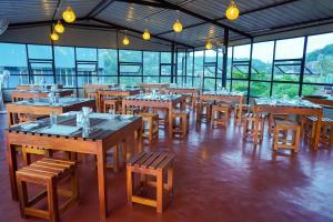 a restaurant with wooden tables and chairs and windows at Vendol Lake Resort - Kandy in Kandy