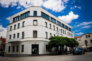 a white building with a tree in front of it at Hotel Opera in Tarnowskie Góry