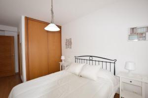 una camera da letto con un letto bianco e una porta di legno di Apartamento Alfredo a O Pindo