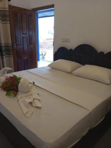 a bed with a white robe and flowers on it at Lilly Pilly Villa Arugambay in Arugam Bay