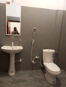 a bathroom with a toilet and a sink and a mirror at Lilly Pilly Villa Arugambay in Arugam Bay