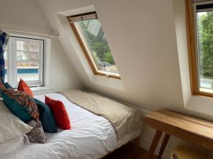 a small bedroom with a bed and two windows at Little Briar in Lyme Regis