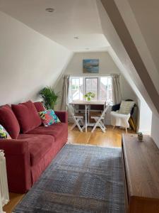 a living room with a red couch and a table at Little Briar in Lyme Regis +13 photos