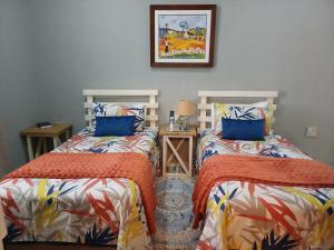 a bedroom with two beds and a picture on the wall at WHY NOT GUESTHOUSE in Bothaville