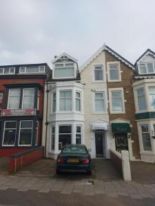 een auto geparkeerd voor een rij huizen bij Witton house in Blackpool