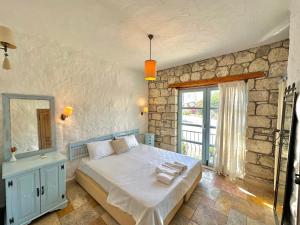 a bedroom with a bed and a stone wall at Dort Mevsim Alacati in Alaçatı