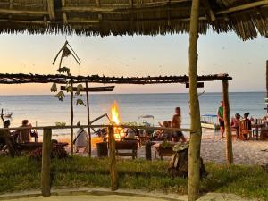 a bonfire at the beach with people sitting around it at Juani beach bungalows in Kilindoni