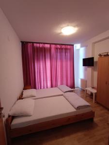a bedroom with two beds and a pink curtain at Prenociste Cazin in Cazin