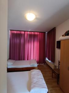 a room with two beds and a window with red curtains at Prenociste Cazin in Cazin +2 photos