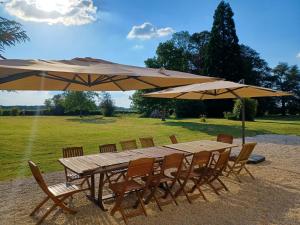 a wooden table and chairs under two umbrellas at Manoir 19e vallée Chevreuse, 30km de Paris in Le Mesnil-Saint-Denis +46 photos
