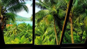 a view of a palm tree from a window at Longtail Beach Resort in Thong Nai Pan Yai