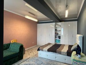 Un dormitorio con una cama, un sofá y una silla. en Dzhal-29, en Bishkek