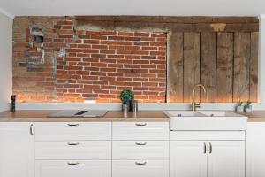 eine Küche mit weißen Schränken und einer Ziegelwand in der Unterkunft ARCTIC HOMES - Historical Tromsø NEWLY RENOVATED in Tromsø