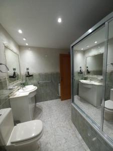 a bathroom with a toilet and two sinks and a shower at Casa Rural El Raso in Almoguera