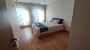 a bedroom with a large bed and two windows at Refúgio do Cais in Esposende