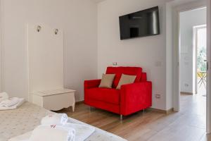 a living room with a red chair and a bed at MILLE SUITE GARDEN in Noto