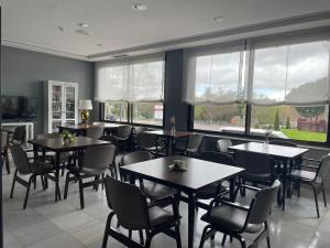 a dining room with tables and chairs and windows at Hotel Don Carmelo in Avila