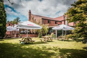 two picnic tables with umbrellas in front of a building at The Barking Buck in Norwich