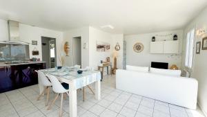 a kitchen and living room with a table and chairs at Jolie maison au calme avec piscine in Rivedoux-Plage