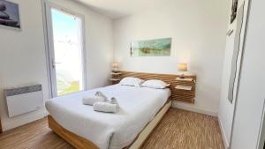a bedroom with a bed with white sheets and a window at Jolie maison au calme avec piscine in Rivedoux-Plage
