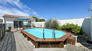 a swimming pool with a wooden deck and a house at Jolie maison au calme avec piscine in Rivedoux-Plage +5 photos