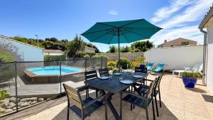 a table with chairs and an umbrella next to a swimming pool at Jolie maison au calme avec piscine in Rivedoux-Plage
