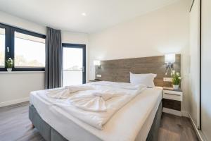 1 dormitorio con 1 cama blanca grande y cabecero de madera en Marina Martinshafen - Lotsenhaus, en Neuhof